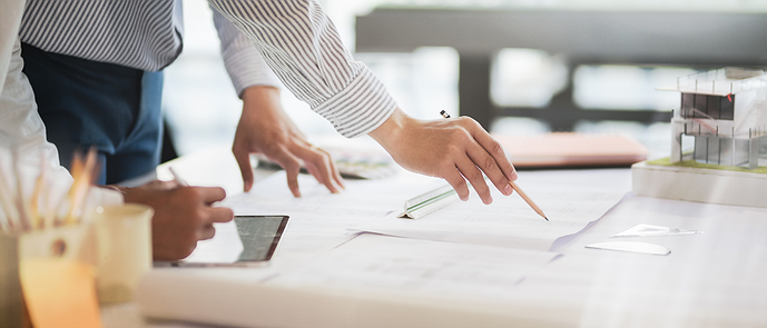 A manager holding a pencil over a desk with papers